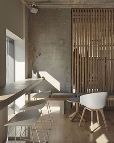 an empty room with wooden slats on the wall and white chairs in front of it