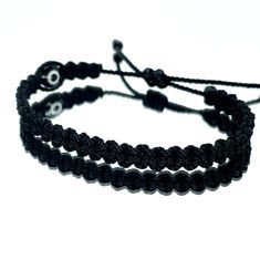 Hand-Made Black String Bracelet With An Evil Eye For Wrist Sizes 6 To 9 Inches, With An Easy To Use Zip Like Function To Fit Your Wrist. Made From High Quality Black String, It Will Be Sure To Last. Wearing An Evil Eye As An Amulet Is Believed To Provide Protection Against Evil Forces. The Evil Eye Meaning Has Symbolism In Almost Every Country In The World And In Every Religion. Each Bracelet Is Carefully Handcrafted And Give Proper Time To Ensure Quality. Casual Black Braided Bracelets For Everyday, Casual Black Wrap Bracelet As Gift, Casual Black Braided Bracelet For Everyday, Casual Black Wrap Bracelet Gift, Casual Black Friendship Bracelet With Black Beads, Casual Black Beaded Bracelets For Friendship, Handmade Black Jewelry For Friendship, Adjustable Black Jewelry Gift, Adjustable Black Jewelry For Gifts