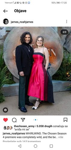 two people standing next to each other in front of a sign