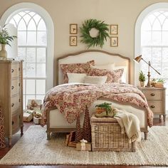 a bed room with a neatly made bed next to two large windows and a rug on the floor