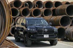 a black toyota truck parked in front of stacks of brown hoses on the street