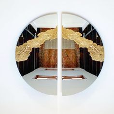 the reflection of a mirror with gold leaf designs on it's sides and an open door to another room