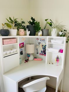 a white desk topped with lots of plants