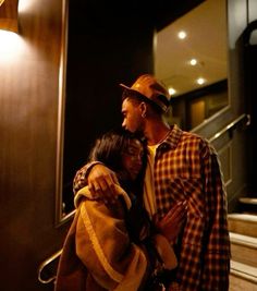 a man and woman standing next to each other in front of an elevator with their arms around each other