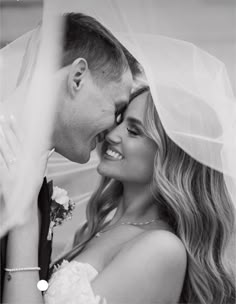 a bride and groom pose for a wedding photo in front of a veiled backdrop