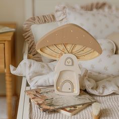 a lamp sitting on top of a bed next to pillows and a magazine with an open book