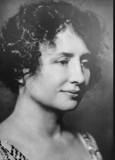 an old black and white photo of a woman with curly hair wearing a patterned dress