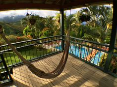 a hammock hanging from the side of a porch next to a swimming pool