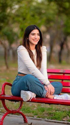 a woman sitting on top of a red bench