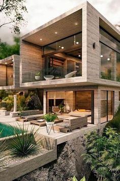 a modern house on the edge of a cliff overlooking a pool and lush greenery