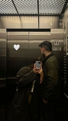 a man standing in front of an elevator holding a cell phone