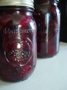 two jars filled with cherries sitting on top of a table