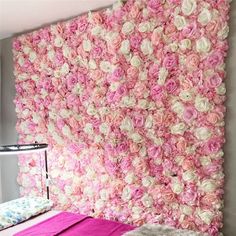 a pink and white flowered wall hanging over a bed