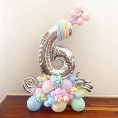 the number six balloon sculpture is decorated with pastel colors and balloons, including flowers