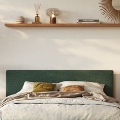 a bed with pillows and blankets on top of it next to a wall mounted shelf