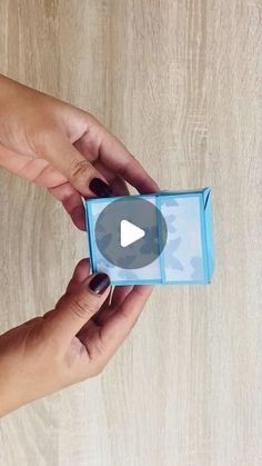 two hands holding an open blue box on a wooden surface