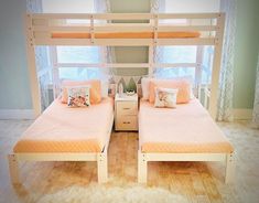 two twin beds in a room with wooden flooring and white curtains on the windowsill