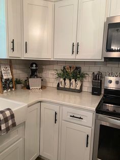 a kitchen with white cabinets and stainless steel appliances