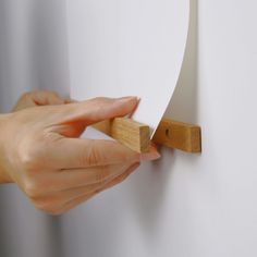 a person is holding a piece of wood to the wall with their hand on it