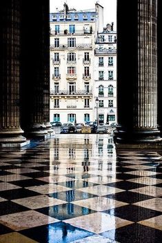 an empty room with columns and checkered flooring in front of a large building