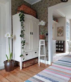 a living room with white furniture and flowers on the wall next to an area rug