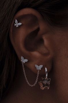 a close up of a person's ear with butterfly earrings on top of it