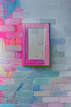 a pink and blue painted brick wall next to a mirror on the side of a building