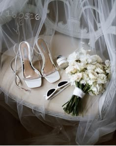 the bride's shoes and bouquet are on the table with veils over them