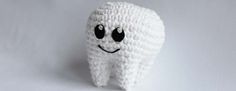 a crocheted tooth with eyes and mouth is shown in front of a white background