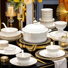 a table topped with lots of white and gold dishes