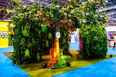 an artificial tree is displayed in the middle of a show floor with people walking around it