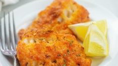 two crab cakes on a white plate with lemon wedges and a fork next to it