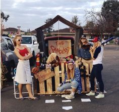 some people are standing in front of a truck with items on it and one person is holding a baseball bat