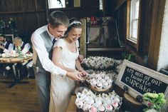 a bride and groom cutting into cupcakes at their wedding reception in the barn