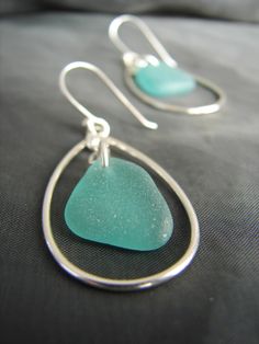 a pair of earrings with sea glass and silver earwires on a black background