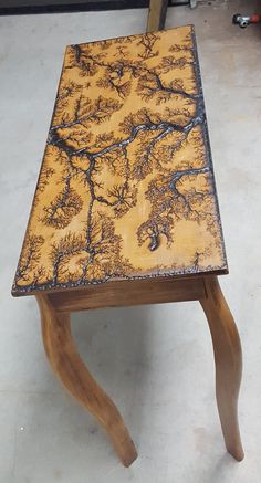 a small wooden table sitting on top of a hard wood floor covered in black and yellow paint