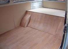 the interior of an rv with wood flooring and window coverings on both sides