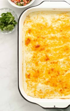 a casserole dish with cheese and other ingredients on the counter top next to it