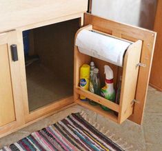 the cabinet door is open to reveal cleaning products and other items in its storage compartment