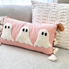 two pillows with ghost faces on them are sitting on a couch next to each other