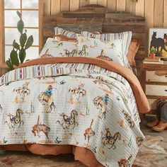 a bed in a room with a cowboy theme on the comforter and pillow cases