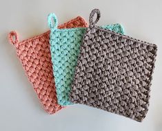 three crocheted bags sitting next to each other on top of a white table