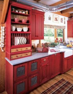 a kitchen with red cabinets and white counter tops