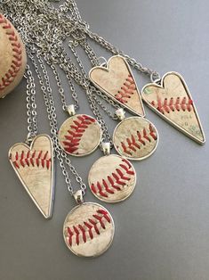 a baseball necklace with six heart shaped softballs attached to it's chain, on a gray surface