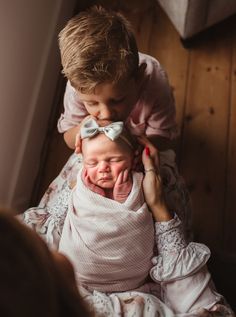 a woman holding a baby in her arms and touching it's face with the other hand