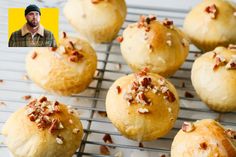 a bunch of muffins that are on a cooling rack with a man in the background