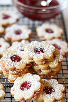 some cookies are on a cooling rack with powdered sugar and raspberry jam