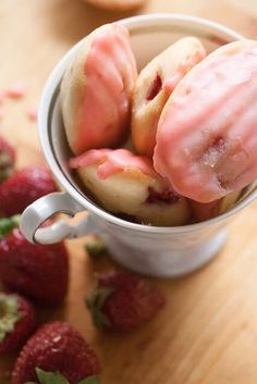 strawberry shortcakes in a cup with pink icing and strawberries on the side