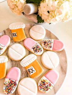 decorated cookies are arranged on a plate with flowers and vases in the back ground