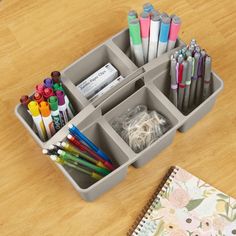 an organized container with markers, pencils, markers and pens on a wooden table